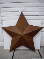 Front view of the large brown metal star showing its five points and faceted design.