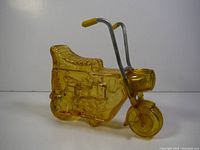 Side view of amber glass minibike decanter showing detailed molded seat, engine and front wheel.