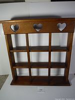 Front view of wooden shelf highlighting three heart-shaped cutouts on top panel and grid layout with 9 compartments