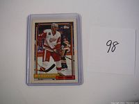 Front view of Nicklas Lidstrom rookie hockey card in protective plastic sleeve next to paper numbered 98.