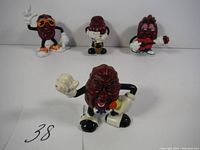 Four California Raisins figurines in a row showing different poses and accessories