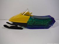 Front-side view of the yellow and translucent blue-purple Ski-Doo shape collectible bottle with intact handlebars and skis.