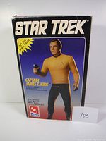 Front of box showing Captain James T. Kirk posed with phaser, 12" vinyl figure size noted.