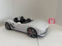 Front angled view of white Baronie 2404XG Alphen convertible model car showing black interior seats, steering wheel, and gray wheels with red brake calipers.