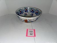 Full view of the handpainted porcelain bowl showing colorful bird and floral motifs inside and outside of the bowl.