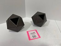 Two black cast iron geometric ball-shaped bookends shown from an angle highlighting their multifaceted surface and triangular openings.