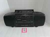 Front view of the black Magnavox Turbo Bass boombox showing speakers, cassette decks, and control panel.