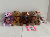 Five Ty Beanie Babies lined up on a white surface, clearly showing their tags and details