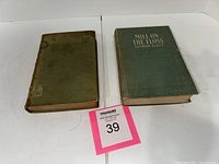 Two vintage hardcover books side by side on white surface; left book is Tennyson's Poetical Works with brownish green cover, heavily worn; right book is Mill on the Floss with green cloth cover and gilt title