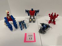 Front view of the five Transformer figures placed on a white surface, showing their different shapes and colors.