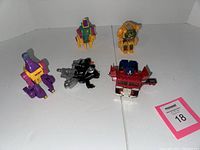 Five small Transformers toys arranged on a white background including a red and blue Optimus Prime and four other figures in various colors.