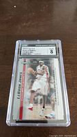 Front view of Lebron James rookie card graded CGC 8 showing action image and card text.