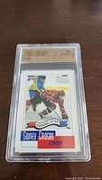 Photo of front of Sidney Crosby pre rookie hockey card graded SPA 10 in protective case showing Crosby in red and a Swedish player in blue and yellow.