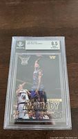 Front view of the 1997-98 Fleer Tracy McGrady rookie card graded BGS 8.5, showing player dunking in purple jersey.