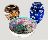 Three Asian ceramic items: a brown Satsuma vase with detailed patterns, a pink and turquoise floral decorative bowl, and a blue and white floral ginger jar with lid
