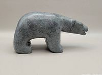 Side profile of small grey Inuit bear stone carving showing the full body shape and minimal features.