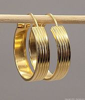 Pair of 18K yellow gold hoop earrings hanging on rod