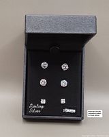 Photo showing all three pairs of sterling silver cubic zirconia stud earrings arranged neatly inside a black DiamonLuxe branded box.