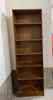 Front view of the tall wooden bookcase showing six shelves and wood grain finish.
