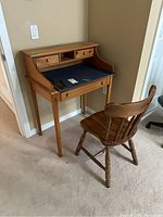 Wooden desk and chair side view showing desk blotter, small drawers, and chair design.