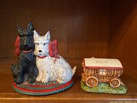 Photo of metal Scotty dogs figurine, painted black and white with red bows, on a red and green base.