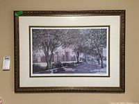 Front-facing photo showing framed print with tree-lined street scene and buildings