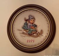 Framed Goebel Hummel collector plate 1975 with child on sled holding lantern and small pine tree