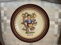 Full view of the round collector plate with a boy sitting on a tree swing, date 1977 visible and brown rim.