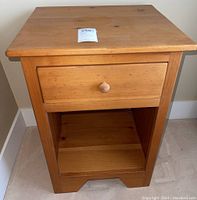 Front view of wooden nightstand showing drawer and open shelf.