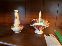 Pair of Royal Albert Old Country Roses ceramic pieces, one vase and one floral basket figurine, on a wooden shelf.