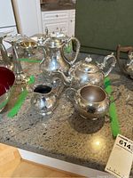 Overview of silverplate coffee pot, teapot, sugar bowl, and creamer set with a green box in background.