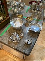 Overview of entire silverplate serving ware set on granite counter showing cream and sugar set, salt and pepper shakers, bowls and other items