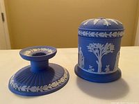 Photo showing both the blue jasperware covered jar with lid and the blue jasperware candleholder side by side on a surface.