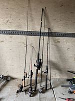 Four fishing rods standing against a wall with reels attached