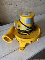Yellow heavy duty utility fan with power cord wrapped on top.