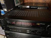 Front and top view of Kenwood VR-616 audio-video surround receiver showing model name, power and speakers buttons, and control knobs for volume and input selection.