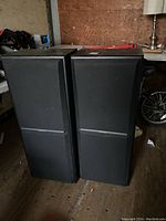 Front view of two black Kenwood floor standing speakers side by side on wooden floor.