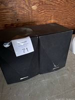 Pair of black Kenwood speakers shown side by side with fabric covers and slight wear on the cabinets.