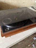 Side view of Pioneer turntable with wood base and clear dust cover.