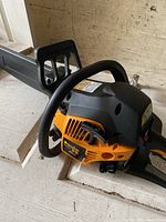 Poulan Pro chainsaw showing orange motor housing, black handle and protective bar cover, placed on a wooden surface.