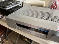 Top-side angled view of silver RCA stereo receiver showing vented metal top and front control panel with buttons and display.