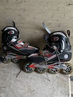 Photo showing one pair of black Rollerblade inline skates, size 11, with four wheels per skate and red and white detailing.