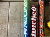Close-up of softball bats showing brand logos and bat colors.