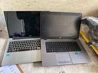 Two laptops placed side by side on a flat surface, showing full front view with screens closed and keyboards visible.