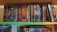 Shelf of DVDs showing variety of fantasy and sci-fi movies including Indiana Jones, Pirates of the Caribbean, Tron, Blade Runner