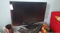 Sharp Aquos 37-inch TV sitting on black stand with remote on top