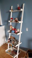Front view of the white leaning ladder shelf against a blue wall with five shelves, showing scale and condition