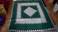 Full view of vintage handmade quilt laid out on a parquet floor showing the geometric pattern.