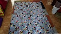 Full view of the vintage handmade quilt laid flat on the floor, showing overall pattern and colors.