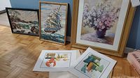 Five pieces of wall art: three framed (flowers print and two paint-by-numbers), two unframed prints laid on floor (lobster and bottles).